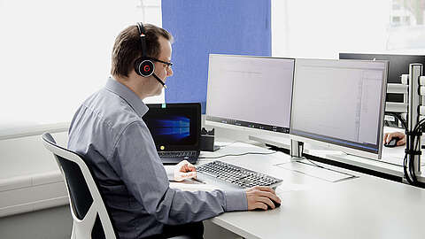 LEITDESK-Mitarbeiter sitzt vor einem PC-Bildschirm und telefoniert mit einem Kunden