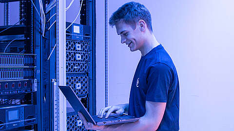 IT Field Service als Schlüssel zu besserer IT-Effizienz Field Service Mitarbeiter blickt auf einen Laptop vor einem Serverschrank
