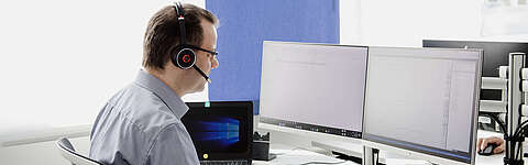 LEITDESK-Mitarbeiter sitzt vor einem PC-Bildschirm und telefoniert mit einem Kunden